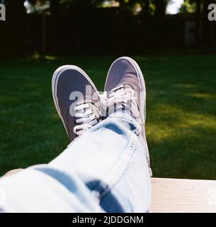 Facile da portare con i piedi in su nel cortile indossando Sneakers Foto Stock