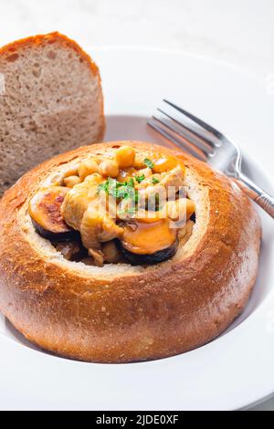 stufato con carne di maiale, ceci e sausge in pane Foto Stock