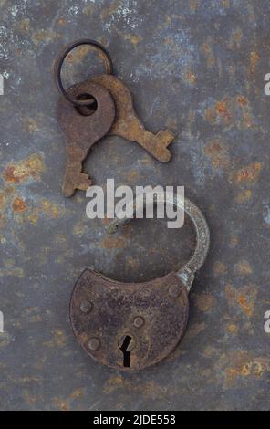 Lucchetto arrugginito su lamiera di metallo arrugginita con coppia di chiavi arrugginite sull'anello Foto Stock