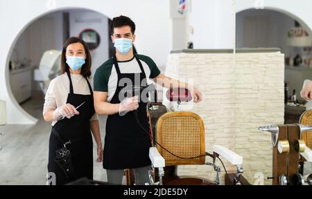 Due parrucchieri in maschere pronte al lavoro Foto Stock