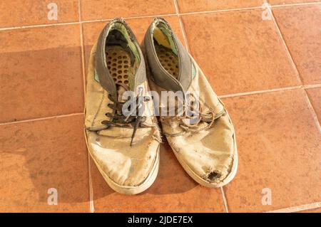 scarpe da uomo vecchie e rotte sul pavimento Foto Stock