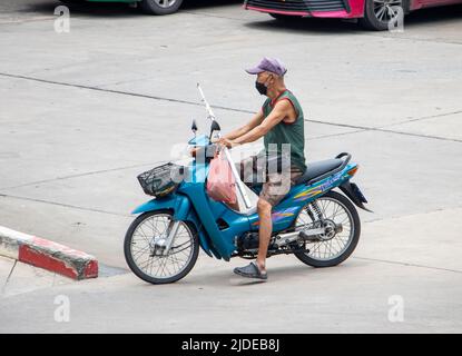 SAMUT PRAKAN, THAILANDIA, MAGGIO 06 2022, SAMUT PRAKAN, THAILANDIA, MAGGIO 06 2022, Un uomo più anziano con maschera di faccia corre una motocicletta sulla strada Foto Stock