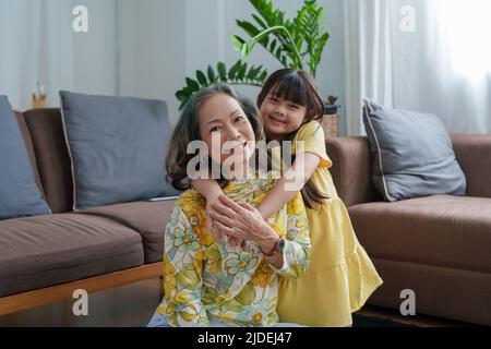 Ritratto asiatico, nonna e nipote che fanno attività di svago e abbraccia per mostrare il loro amore e la cura per gli altri Foto Stock