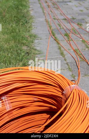 Fascio di cavi in fibra ottica arancione avvolti sulla strada, pronti per entrare a terra. Internet veloce. Messa a fuoco davanti Foto Stock