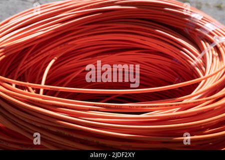 Fascio di cavi in fibra ottica arancione avvolti sulla strada, pronti per entrare a terra. Internet veloce. Messa a fuoco davanti Foto Stock