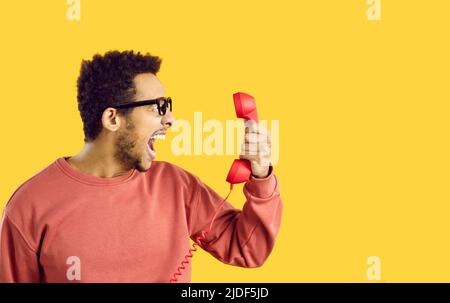 Furioso giovane afroamericano pieno di rabbia gridando al telefono Foto Stock