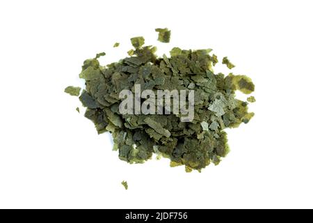 Verde cibo secco in forma di fiocchi per pesci acquario su sfondo bianco è versato in una manciata. Vista dall'alto Foto Stock