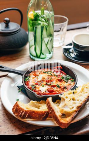 Shakshuka in padella di ferro servito con pane Foto Stock