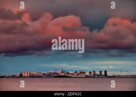 Cielo rosa magico sopra il complesso residenziale in costruzione sul lungofiume del fiume Neva sull'isola di Vasilievsky al tramonto, isola alla rinfusa Foto Stock