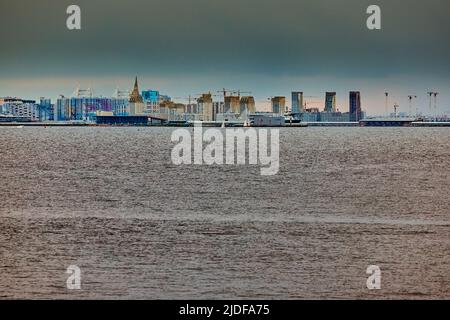 Il complesso residenziale in costruzione sul lungofiume del fiume Neva sull'isola di Vasilievsky al tramonto, isola bulk, gru da costruzione Foto Stock