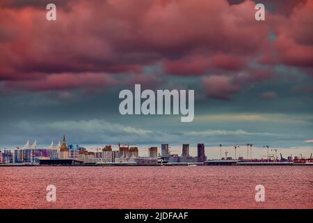 Cielo rosa magico sopra il complesso residenziale in costruzione sul lungofiume del fiume Neva sull'isola di Vasilievsky al tramonto, isola alla rinfusa Foto Stock