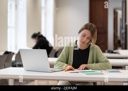 Studentessa di mezza età focalizzata si prepara per il lavoro di corso nella scuola superiore universitaria o nel campus universitario Foto Stock