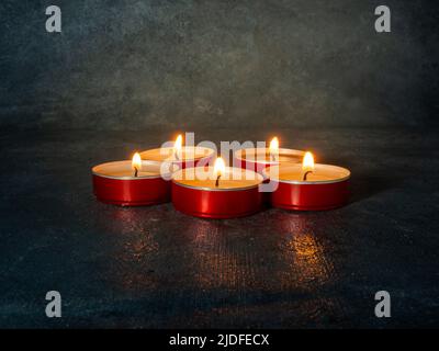 Un sacco di piccole candele accese. Dark Mysterious atmosphere.Candle background.Flat candele rotonde in rosso metallo stand Foto Stock