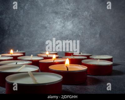 Un sacco di piccole candele accese. Atmosfera oscura e misteriosa. Sfondo  candela. Candele piatte rotonde Foto stock - Alamy