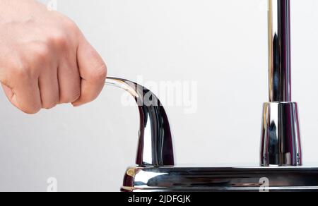 Maniglia di presa a mano e rubinetto dell'acqua aperto, vista ravvicinata isolata Foto Stock