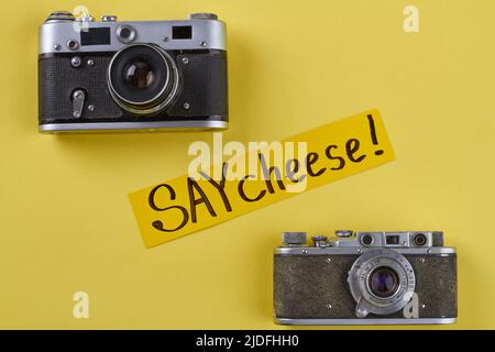 Due fotocamere d'epoca su sfondo giallo. Dite la scrittura a mano del formaggio. Foto Stock