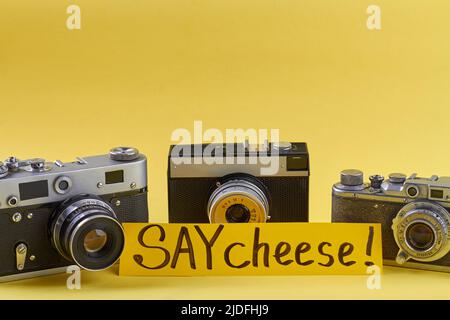 Tre fotocamere retro isolate su sfondo giallo. Raccolta di camer vintage da vicino. Dite formaggio! Foto Stock