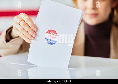 Primo piano di una giovane donna che mette in votazione il cestino contro la bandiera americana sfondo, copia spazio Foto Stock