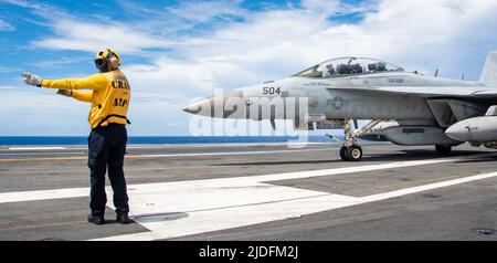 220618-N-BR419-1169 PHILIPPINE SEA (18 giugno 2022) Aviation Boatswain’s Mate (Handling) 1st Class Guillermo Segura, di Lawton, Oklahoma, dirige un EA-18G Growler attaccato agli Shadowhawks of Electronic Attack Squadron (VAQ) 141, sul ponte di volo dell'unica compagnia aerea statunitense USS Ronald Reagan (CVN 76). Il ruolo principale di EA-18G Growlers è quello di interrompere la capacità di comunicare tra le unità in combattimento attraverso l'uso di guerra elettronica. Ronald Reagan, l'ammiraglia del Carrier Strike Group 5, fornisce una forza pronta per i combattimenti che protegge e difende gli Stati Uniti Foto Stock