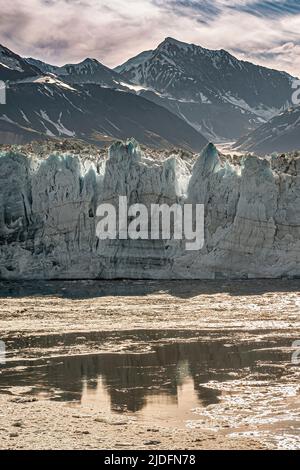 Disincantment Bay, Alaska, USA - 21 luglio 2011: Ritratto primo piano della parete del ghiacciaio Hubbard come raggiunge l'acqua dell'oceano sotto il paesaggio blu e mou Foto Stock