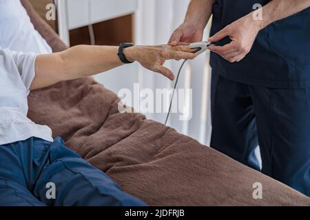 Controllo del personale infermieristico con la saturazione di ossigeno pulsossimetrica del sangue del paziente in ospedale Foto Stock