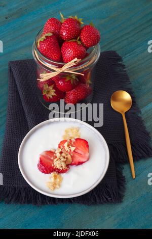 Ciotola di fragole fresche con creme fraiche e nocciole, gustoso dessert di frutta, niente gente, closeup ad angolo alto. Foto Stock