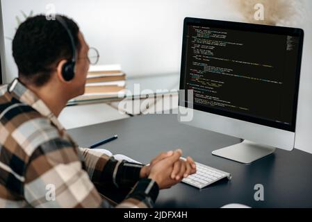 Sviluppo di tecnologie di codifica, software. Clever IT Specialist, programmatore, utilizza il computer, lavorando allo sviluppo di un sito web, nuova applicazione, scrittura di codici e codice dati. Dati digitali sullo schermo Foto Stock