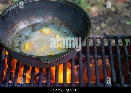 La gustosa patate ruddy è friggere in calderone in olio sulla natura sul fuoco, vista closeup. Foto Stock