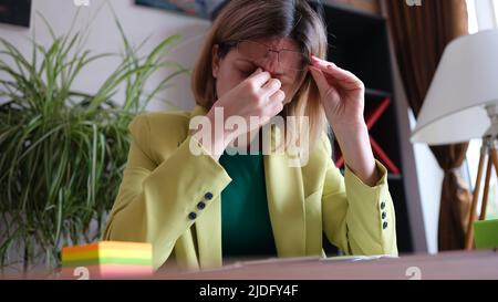 Donna sovraccarica seduta sul posto di lavoro in ufficio Foto Stock