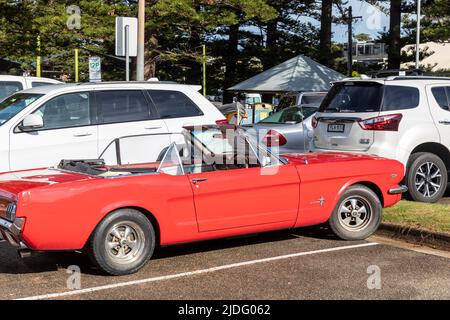 1966 Ford Mustang rosso convertibile parcheggiato a Newport Beach a Sydney, Australia una classica auto da spiaggia americana Foto Stock