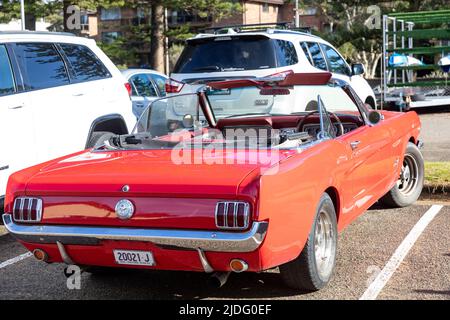 Red Ford Mustang convertibile costruito nel 1966, con tetto giù, parcheggiato a Newport Beach a Sydney, Australia con storico targa Foto Stock