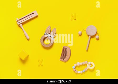 Diversi accessori in legno per il bambino su sfondo giallo Foto Stock