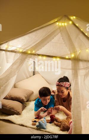 Madre che aiuta il figlio a riparare la macchina di legno rotto giocattolo Foto Stock