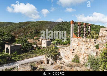 Facciate deteriorate e parti metalliche arrugginite nelle rovine della miniera abbandonata di Naracauli nei pressi di Ingurtosu, Costa Verde, Sardegna, Italia Foto Stock