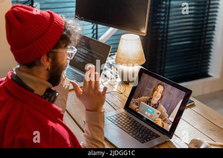 Uomo che ha incontri online con una collega, mentre lavora a casa Foto Stock