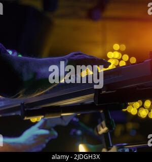 Un pianista o tastierista suona sul palco un sintetizzatore sotto i riflettori. Tasto scuro. Messa a fuoco selettiva soft Foto Stock