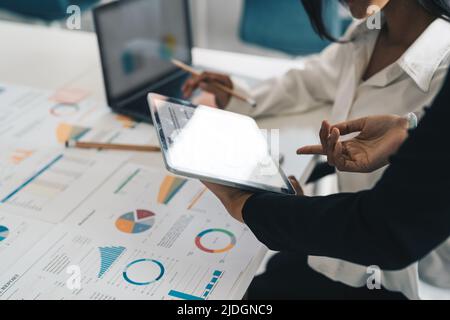 Colleghi della partnership aziendale che utilizzano il tablet digitale per inserire i report dei bilanci aziendali e i profitti dei progressi e della pianificazione del lavoro in ufficio Foto Stock