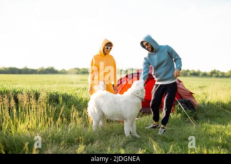 Le giovani coppie giocano con il loro cane al campeggio Foto Stock