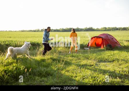 Le giovani coppie giocano con il loro cane al campeggio Foto Stock