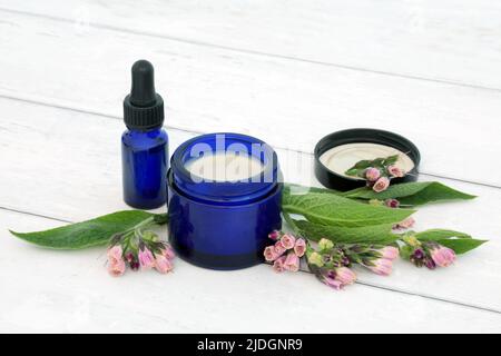 Unguento di erbe di Comfrey e olio essenziale usato in medicina naturale della pianta di erbe per trattare i problemi della pelle compreso bruciature, gonfiamento, spruins, lividi. Foto Stock