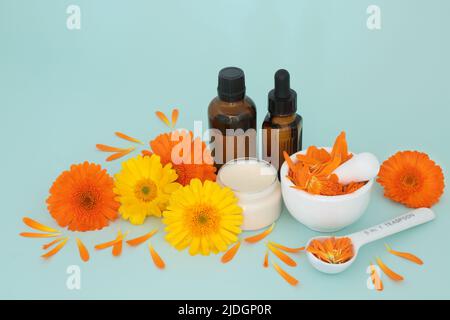 Calendula fiori per la cura della pelle con unguento, bottiglie di olio essenziale e petali in un mortaio. Guarisce ferite, acne, eczema, stimola il collagene, . Foto Stock