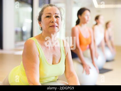 Maturo femmina esecuzione serie di esercizi con pilates palla Foto Stock