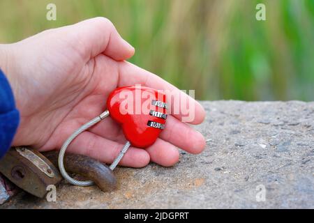Mano che tiene un blocco d'amore a forma di cuore chiuso all'aperto. Concetto di relazioni forti creative. Foto Stock