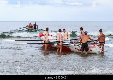 Bagnini che lanciano barche da surf mentre si allenano al Monte Maunganui, Nuova Zelanda Foto Stock