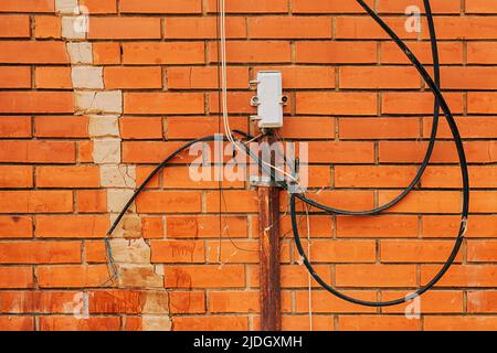 Scatola di derivazione esterna per collegamento telefonico esterno con cavi e fili disordinati su una parete in mattoni Foto Stock