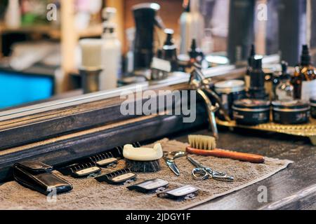 Barbershop haircut strumenti attrezzature barbiere sul fronte in legno del controsoffitto dello specchio, interni in vecchio stile vintage. Utensili per parrucchieri per taglio capelli alla moda, cl Foto Stock