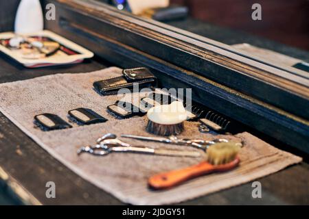 Barbershop haircut strumenti attrezzature barbiere sul fronte in legno del controsoffitto dello specchio, interni in vecchio stile vintage. Utensili per parrucchieri per taglio capelli alla moda, cl Foto Stock