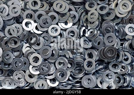 Gruppo di rondelle piane zincate in acciaio inox per viti di fissaggio, dadi o bulloni, fondo bulloneria. Pila di rondelle piatte per la distribuzione del carico di Foto Stock