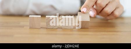 Donna di affari che capovolgono un cubo di legno dalla fila Foto Stock