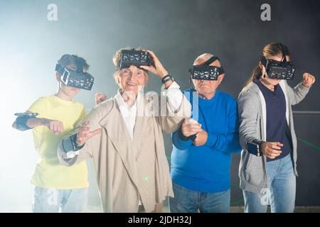 Nonni e nipoti che giocano insieme ai videogame di realtà virtuale Foto Stock